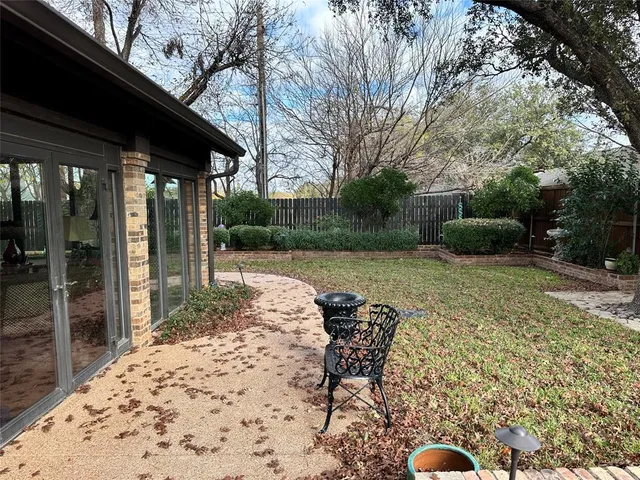 a view of a backyard with table and chairs potted plants and large tree