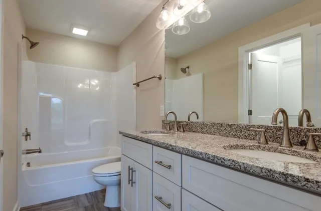 a bathroom with a granite countertop sink a toilet a bathtub and shower