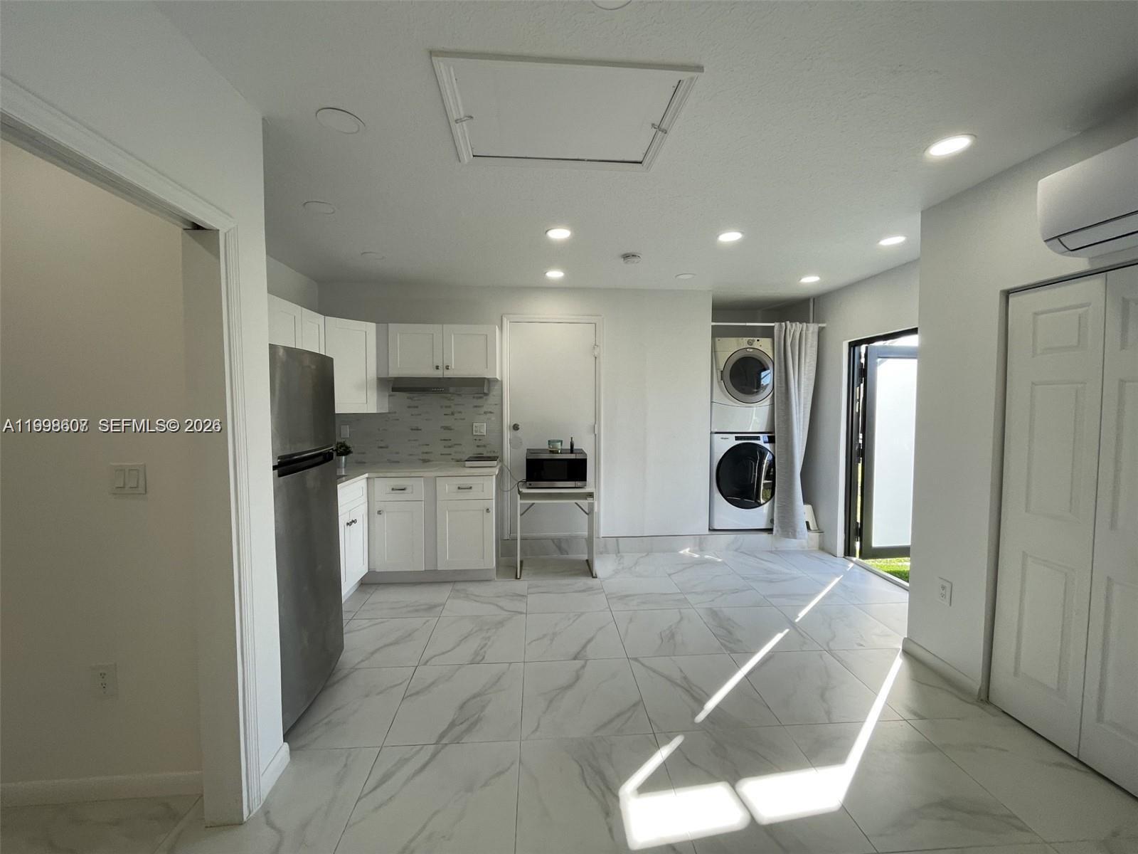 a large white kitchen with stainless steel appliances kitchen island a refrigerator and a stove