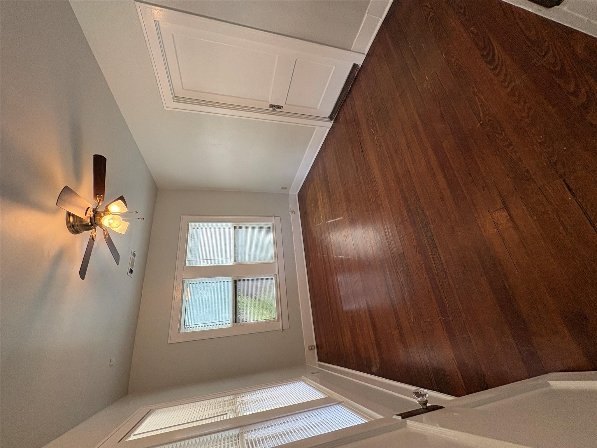 915 West 29th Street Austin, TX 78705 - Photo 4 of 20 Hardwood flooring throughout, featuring a ceiling fan with integrated lighting, two windows with blinds, and white trim molding