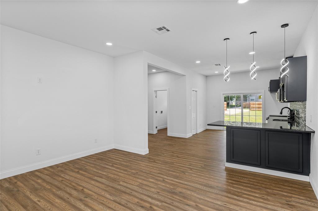 2023 Bosque Boulevard Waco, TX 76707 - Photo 7 of 26 Open-concept living space featuring wood-finish flooring, recessed lighting, and a kitchen island with dark cabinetry and a dark countertop