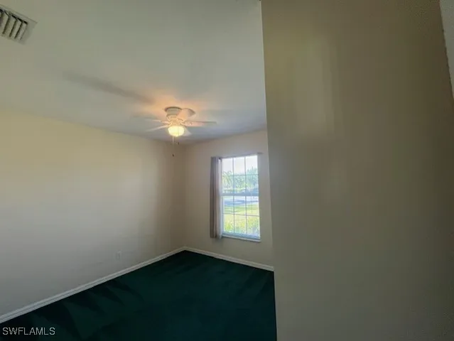 an empty room with chandelier fan and windows
