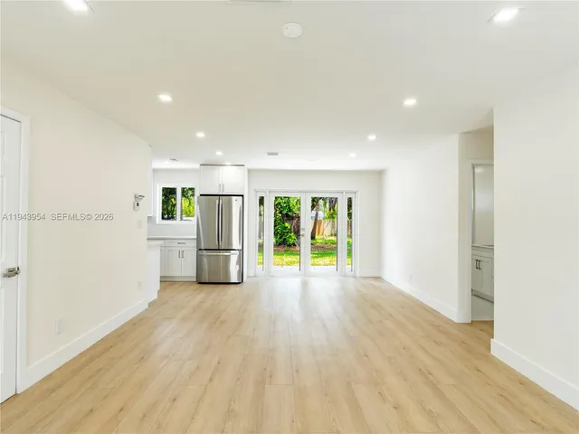 a view of an empty room with a window and wooden floor