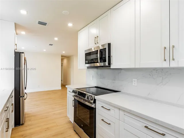 a kitchen with stainless steel appliances white cabinets and wooden floor