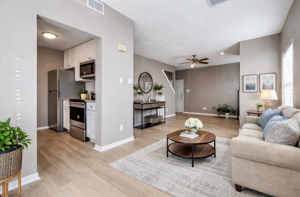 Staged living room with ceiling fan and light wood-style flooring