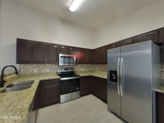 an empty room with wooden floor chandelier fan and windows