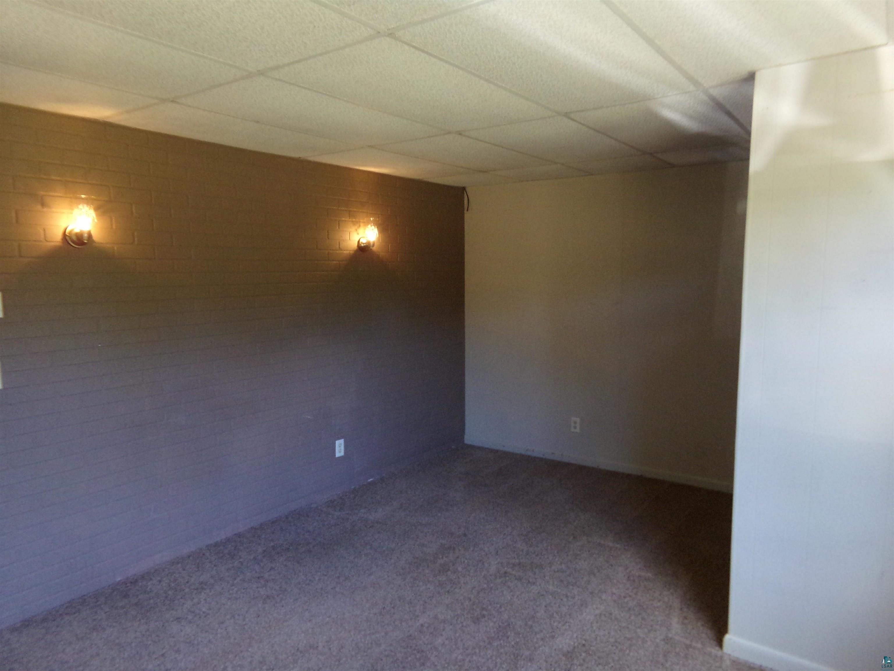 Spare room featuring dark carpet and a paneled ceiling