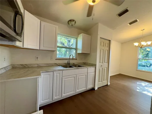 a kitchen with stainless steel appliances granite countertop a sink a stove a refrigerator a washer dryer and white cabinets with wooden floor