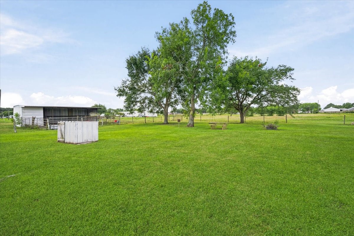 765 Norcross Road Wallis, TX 77485 - Photo 32 of 42 Expansive green yard with mature trees, fenced area, and a small outbuilding, perfect for enjoying outdoor space and privacy.