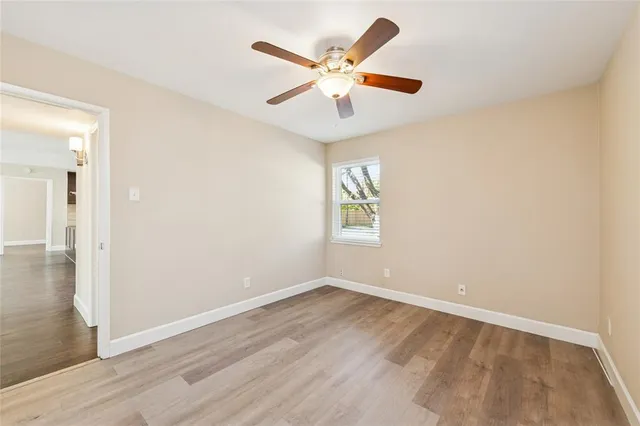 an empty room with wooden floor and ceiling fan