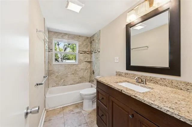 a bathroom with a granite countertop sink mirror vanity bathtub and toilet