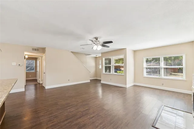an empty room with wooden floor chandelier and windows