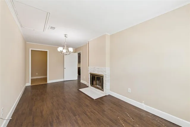 an empty room with wooden floor fireplace and staircase