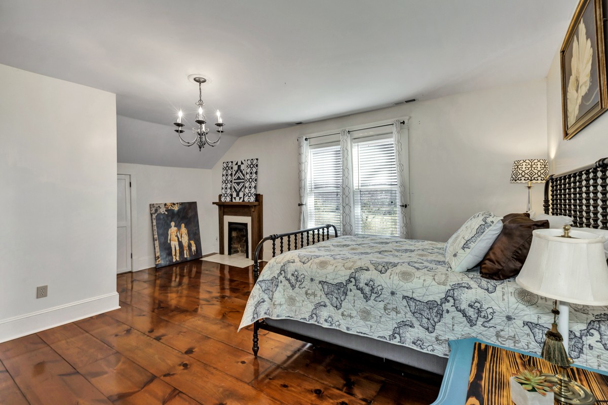 451 Wheelerton Road Dellrose, TN 38453 - Photo 20 of 34 a bedroom with a bed a chandelier and dresser with wooden floor