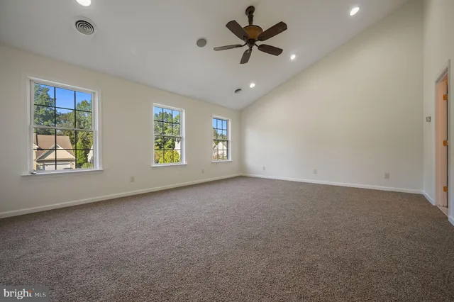 an empty room with windows and ceiling fan