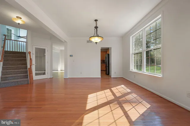 a view of an empty room with window and wooden floor