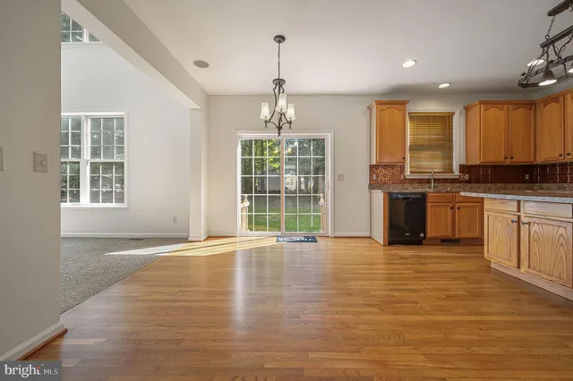 a view of an empty room with a kitchen stove and wooden floor