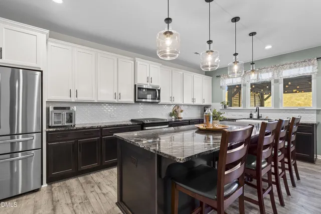 a kitchen with kitchen island granite countertop a sink a center island and stainless steel appliances