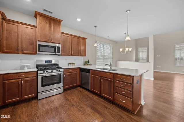 a kitchen with stainless steel appliances granite countertop a stove a sink dishwasher and a microwave oven with wooden floor
