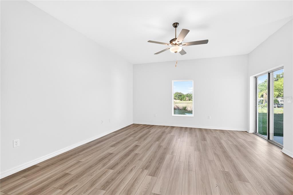 13430 Leaping Water Way Astatula, FL 34705 - Photo 12 of 55 an empty room with wooden floor chandelier fan and windows