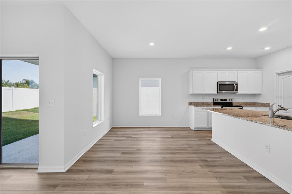 13430 Leaping Water Way Astatula, FL 34705 - Photo 14 of 55 a large white kitchen with kitchen island a sink wooden floor and a refrigerator
