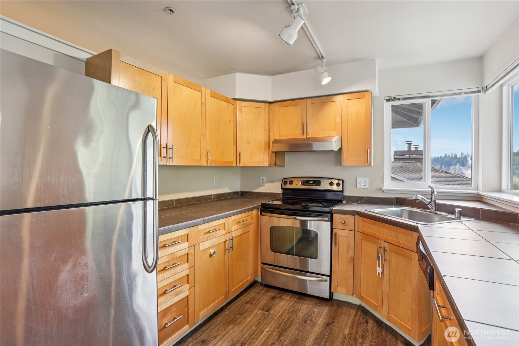 3927 243rd Place Southeast, Unit I304 Bothell, WA 98021 - Photo 10 of 28 a kitchen with stainless steel appliances granite countertop a refrigerator a sink dishwasher a stove with white cabinets and wooden floor
