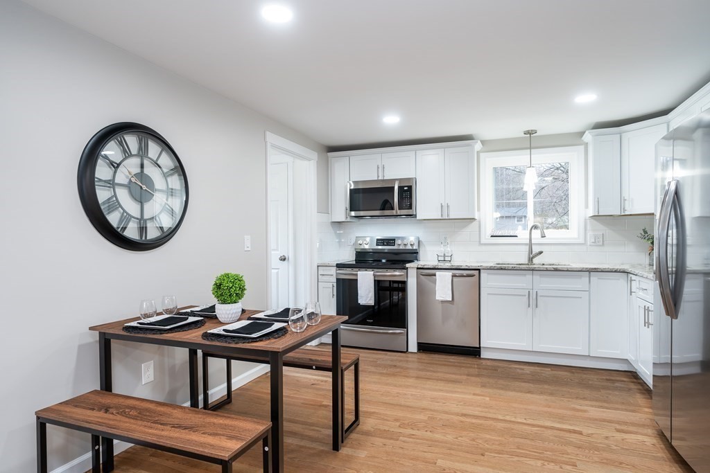 152 Shady Brook Lane Springfield, MA 01118 - Photo 4 of 26 a kitchen with stainless steel appliances a dining table a stove a refrigerator cabinets and a dining table