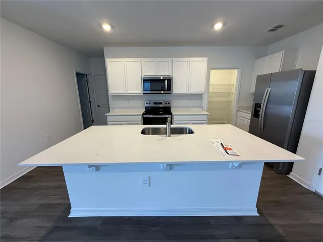 a room with wooden floor and stainless steel appliances