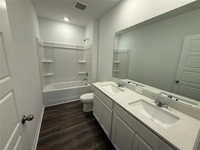 a bathroom with a double vanity sink toilet mirror and shower