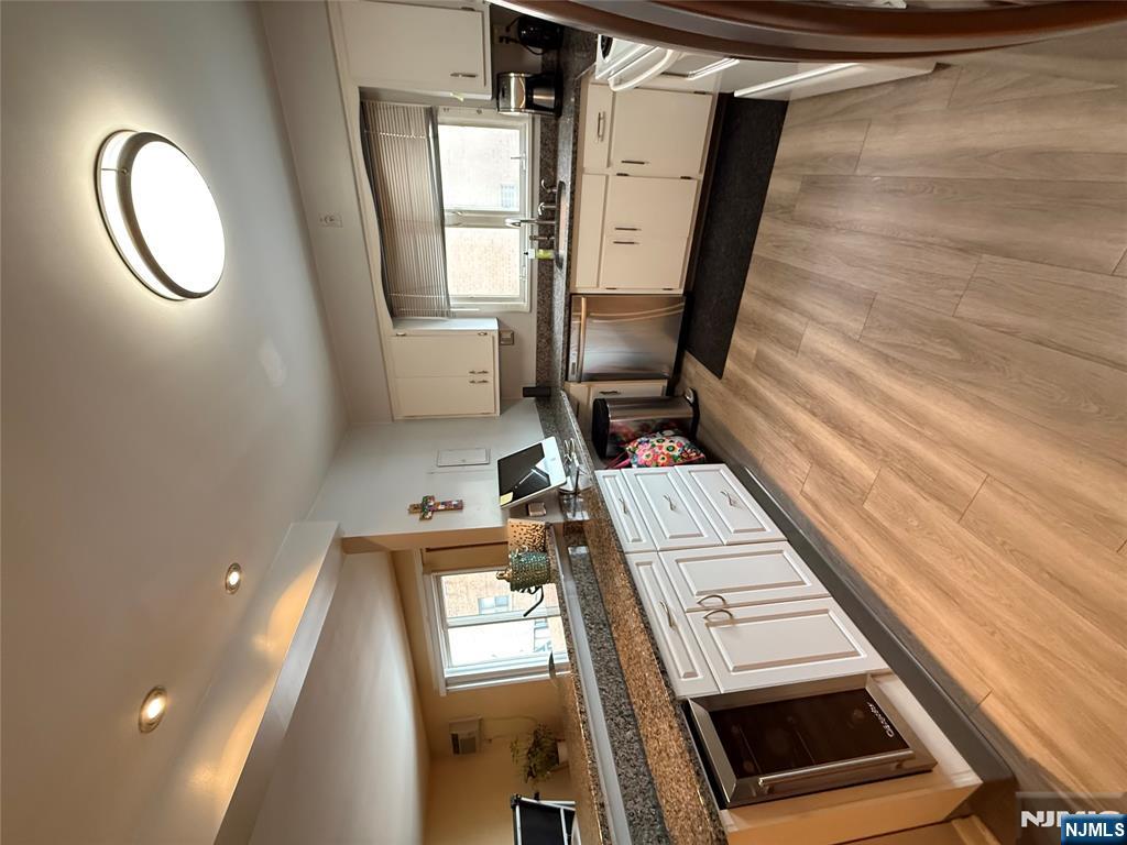101 Orient Way, Unit 2C1 Rutherford, NJ 07070 - Photo 4 of 12 a large kitchen with granite countertop a stove top oven a sink dishwasher and white cabinets with wooden floor