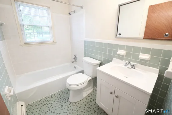 a bathroom with a sink toilet a mirror and bathtub