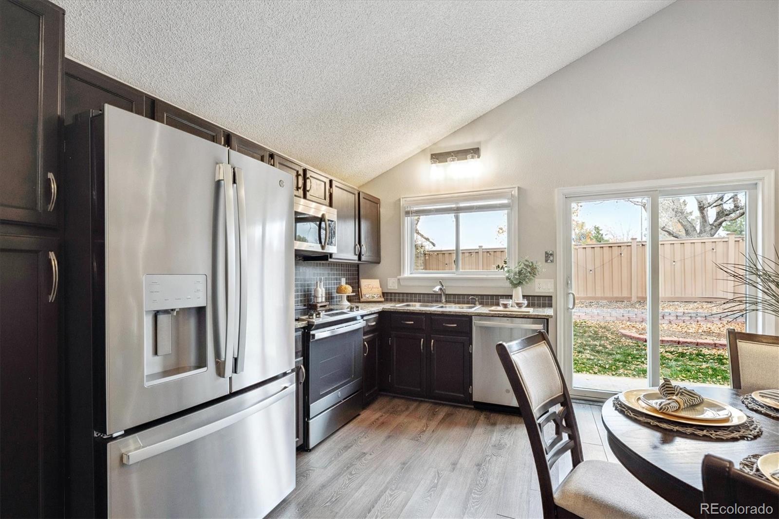 669 Walden Court Highlands Ranch, CO 80126 - Photo 14 of 34 a kitchen with stainless steel appliances granite countertop a refrigerator a stove a sink dishwasher and white cabinets with wooden floor