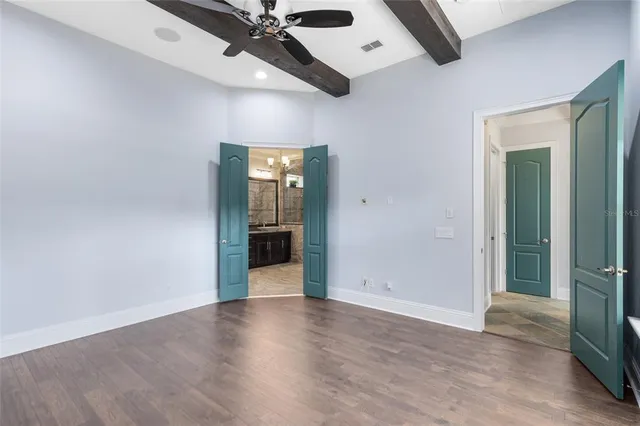 an empty room with wooden floor cabinet and windows