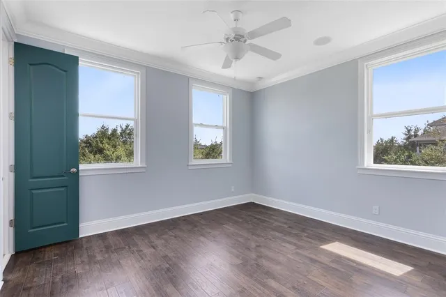 a view of an empty room with a window and wooden floor