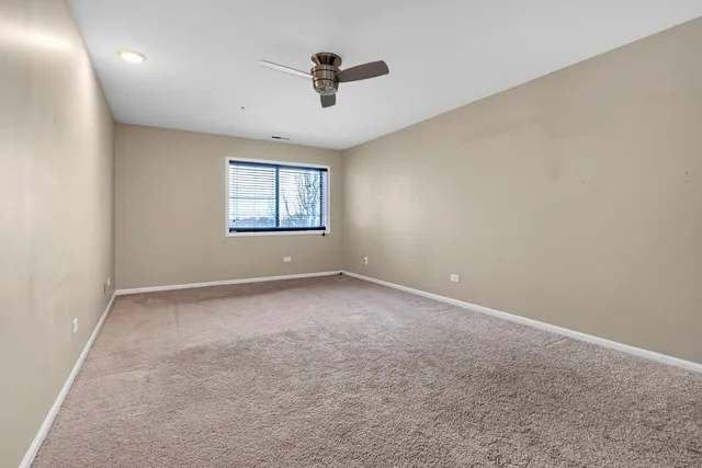 an empty room with ceiling fan and windows