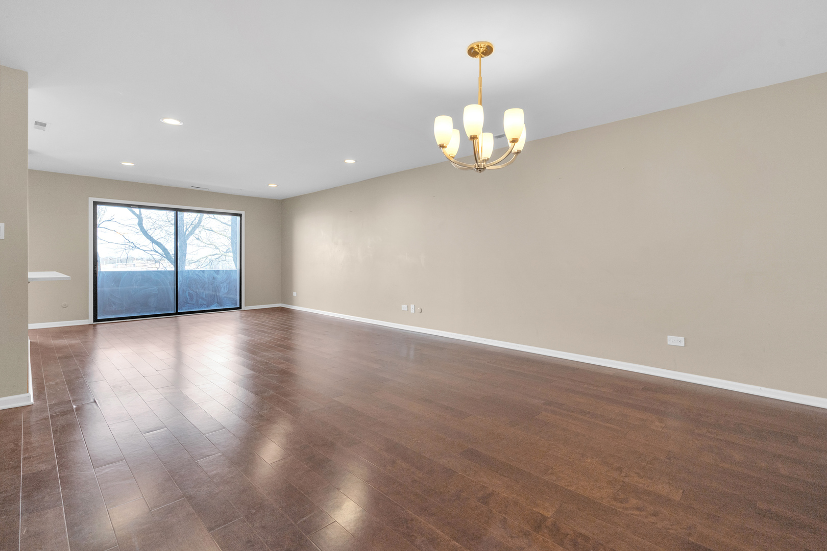 9242 Gross Point Road, Unit 310 Skokie, IL 60077 - Photo 3 of 18 an empty room with wooden floor and chandelier