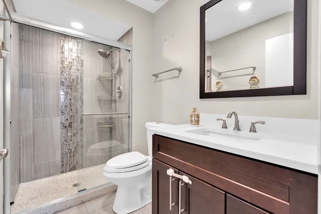 a bathroom with a granite countertop sink toilet a mirror a vanity and shower