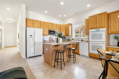 a kitchen with stainless steel appliances a refrigerator a stove a sink a dining table and chairs with wooden floor