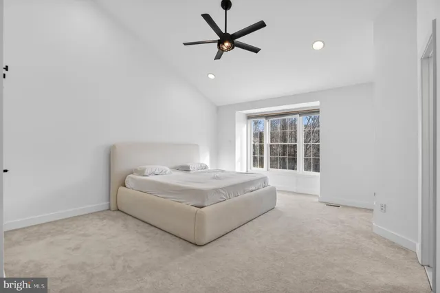 a white bed sitting in a room next to a window