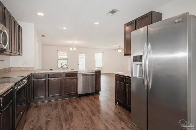 a kitchen with refrigerator and wooden floor