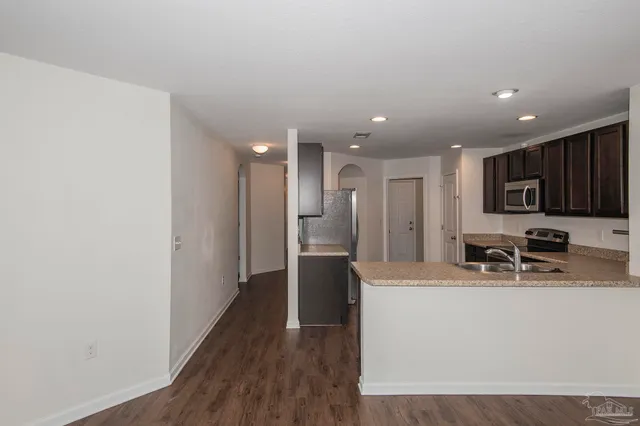 a kitchen with stainless steel appliances granite countertop a refrigerator a sink a stove and oven with wooden floor