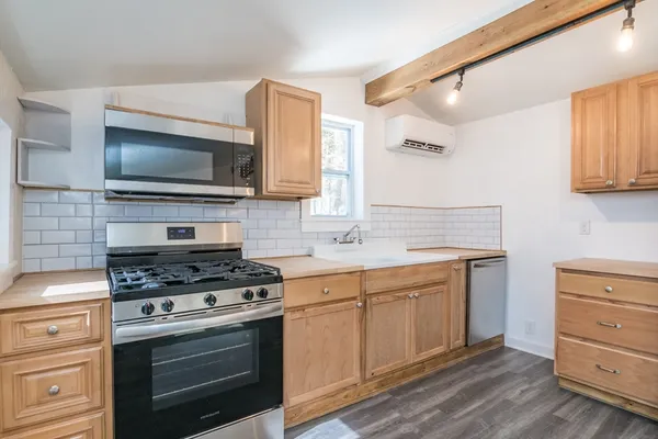 a kitchen with cabinets stainless steel appliances and wooden floor