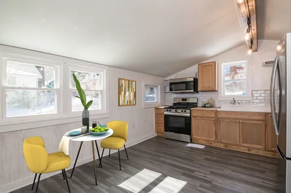a kitchen with stainless steel appliances granite countertop a refrigerator a stove a sink dishwasher with a dining table and chair with wooden floor