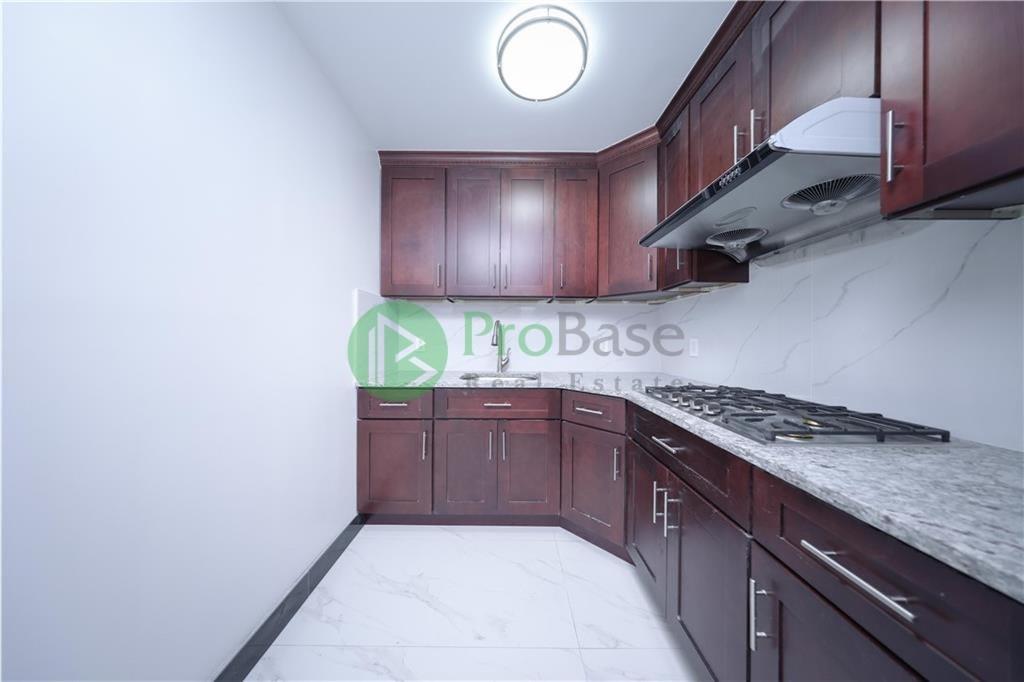 2837 West 19th Street, Unit 3B Brooklyn, NY 11224 - Photo 10 of 21 a kitchen with granite countertop wooden cabinets and a stove