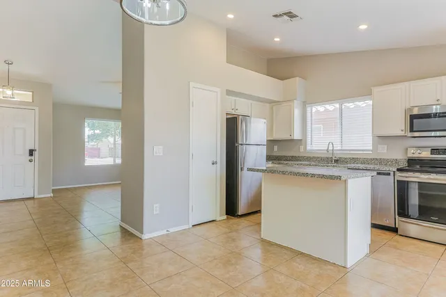 a kitchen with kitchen island granite countertop appliances cabinets and a sink
