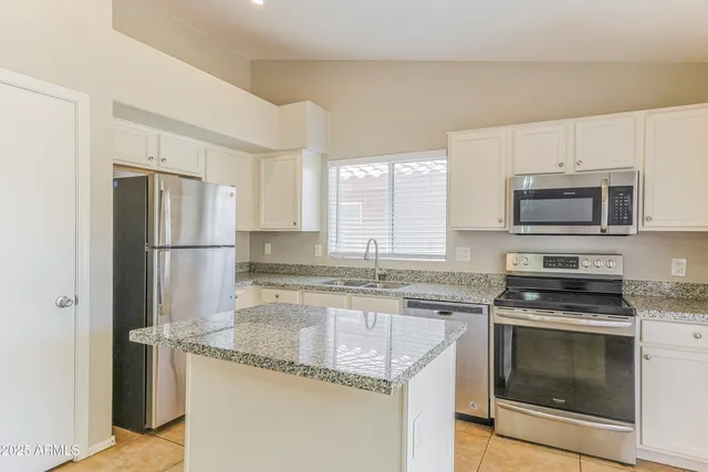 a kitchen with granite countertop a refrigerator stove and microwave