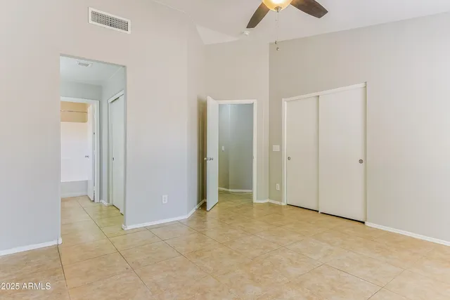 an empty room with closet and a chandelier fan