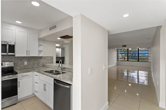 a kitchen with kitchen island granite countertop a refrigerator and a stove top oven