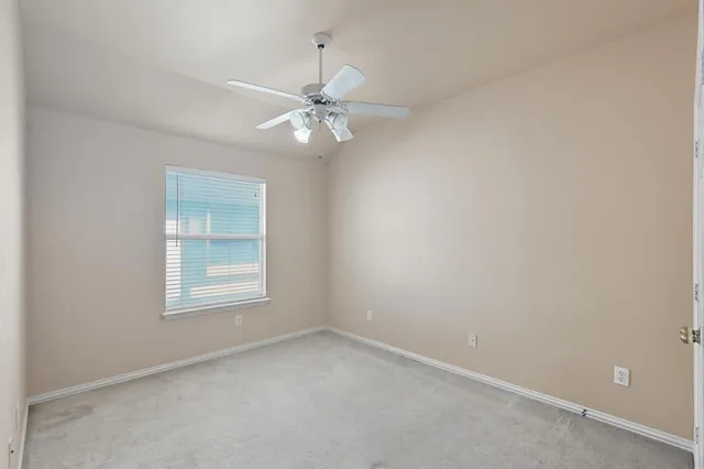 an empty room with a chandelier fan and closet area