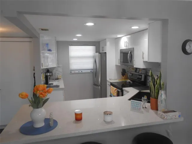 a kitchen with stainless steel appliances granite countertop a sink a refrigerator and a granite counter tops